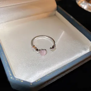 Primo piano di un anello aperto in argento con cuore rosa e dettagli floreali in zircone