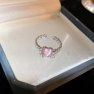 Primo piano di un anello in argento con una pietra a cuore rosa e zirconi