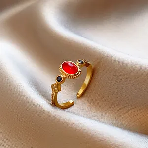 Primo piano di un anello dorato vintage con pietra rossa e dettagli in zircone