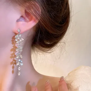 Close-up of elegant silver tassel earrings with leaf-shaped rhinestones