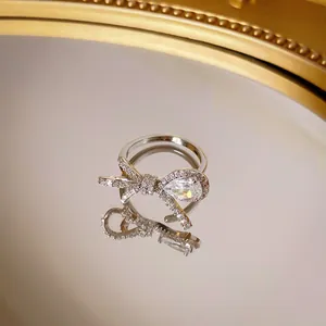 Elegante anello a fiocco d'argento con pietre di zircone su una superficie a specchio
