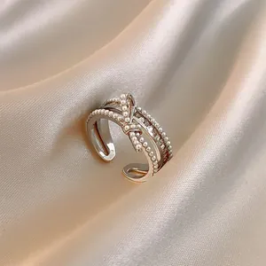 Anello a fiocco in argento con perle e zirconi su morbido tessuto di seta champagne