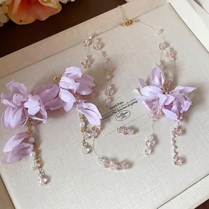 Elegant purple fabric flower and pearl jewelry set including necklace and earrings.