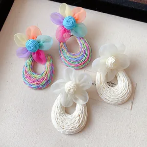 Close-up of Bohemian style mesh flower earrings with woven hoops for beach vacation.