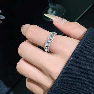 Primer plano de un elegante anillo abierto con circonitas onduladas y perlas falsas
