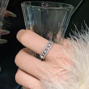 Detalle de un elegante anillo plateado ondulado con circonitas y perlas falsas