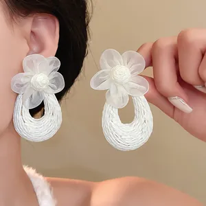 Detailed view of white bohemian mesh flower earrings with elegant woven teardrop base