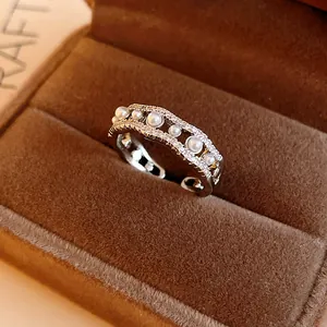 Detalle macro de elegante anillo abierto ondulado plateado con circonitas y perlas sintéticas