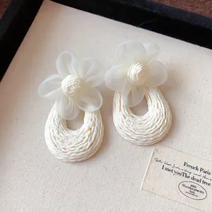Detailed view of elegant Bohemian mesh flower earrings with a cream woven texture