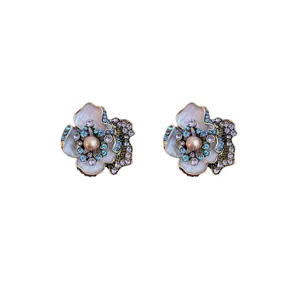 Vintage silver needle flower stud earrings with blue rhinestones and a central pearl.