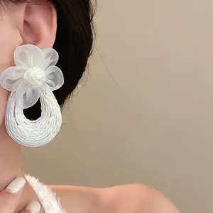 Detailed close-up of bohemian white mesh flower earrings with woven drop design