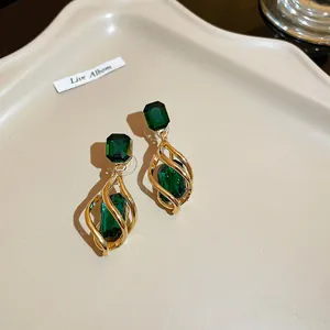 Elegant gold twisted cage drop earrings featuring brilliant emerald green stones