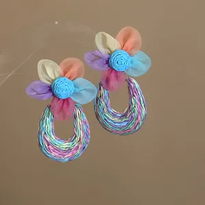 Detailed view of bohemian mesh flower earrings with colorful woven U-shaped drops