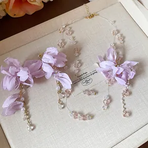 Detail view of purple fabric flower and pearl jewelry set including necklace and earrings