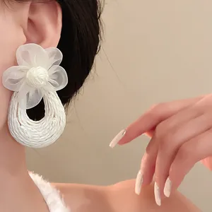 Close-up detail of white mesh flower earring featuring a Bohemian style woven hoop design