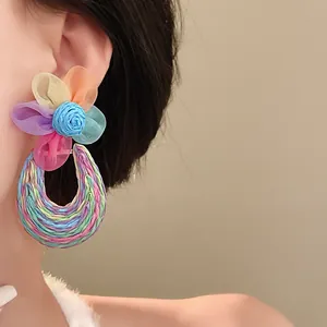 Detail shot of colorful mesh flower earrings with bohemian woven hoop on Asian model