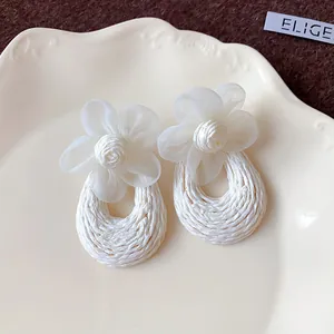 Macro view of elegant white mesh flower earrings featuring a bohemian woven design.