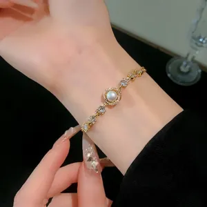 Elegant gold-plated bracelet with pearl and zircon inlay, worn on a female wrist.