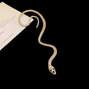 Gros plan d'un ear cuff serpent doré orné de strass brillants et très éclatants