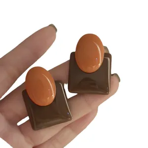 Retro geometric resin stud earrings featuring an orange oval on brown square base.