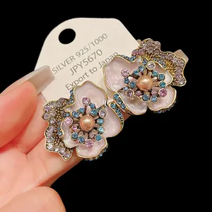 Close-up detail of retro pink enamel flower earrings featuring pearls and blue crystals