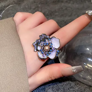 Macro view of a vintage style floral ring featuring blue crystals and a center pearl inlay