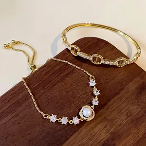Detailed macro view of gold-plated zircon bangle and pearl bracelet on a wooden display stand