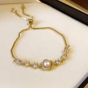 Detailed macro view of an elegant gold-plated adjustable bracelet with pearls and zircons