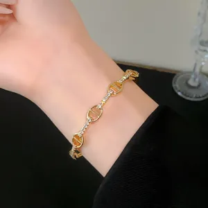 Close-up detail of a gold plated pig nose bracelet with sparkling zircons on a wrist