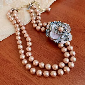 Close-up of elegant double-strand pearl necklace with blue rhinestone flower pendant