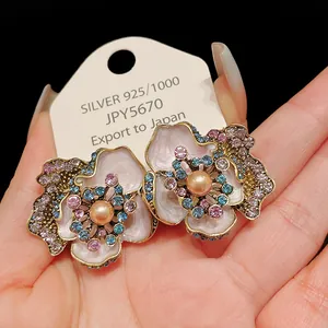 Close-up of vintage flower earrings with colorful rhinestones and center pearl detail