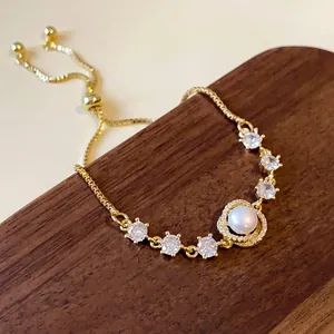 Detailed close-up of gold-plated bracelet with white zircons and center pearl