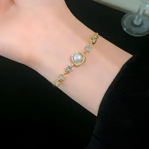 Elegant gold-plated bracelet featuring a central pearl and sparkling zircons on a wrist