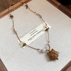 Détail du collier vintage avec pendentif étoile en œil de tigre, perles et carte de vœux