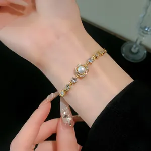 Detailed close-up of elegant gold plated bracelet with pearl and sparkling zircon stones