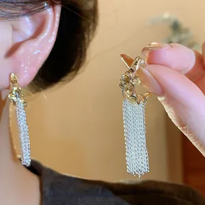 Close-up of elegant gold and silver tassel earrings featuring a delicate mesh fringe