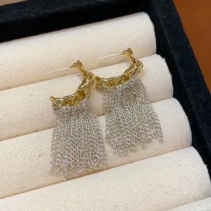 Detailed macro view of golden irregular molten earrings with silver chain tassels