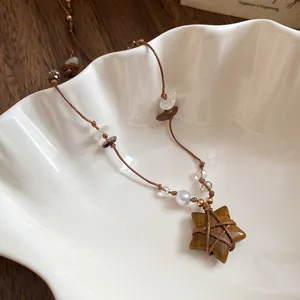 Gros plan détaillé d'un collier pendentif étoile en œil de tigre vintage avec cordon