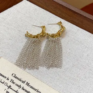 Close-up view of elegant gold and silver chain tassel earrings with a unique textured base