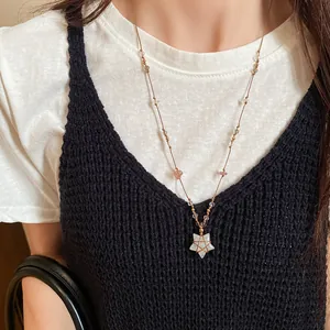 Gros plan d'un collier avec pendentif étoile vintage et perles porté par un mannequin chic