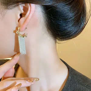 Close-up detail of elegant gold-tone earrings with silver chain tassel on a model