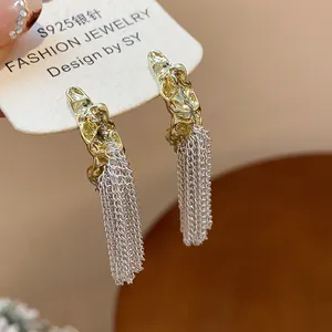 Close-up detail of gold-toned textured earrings with elegant silver chain tassels