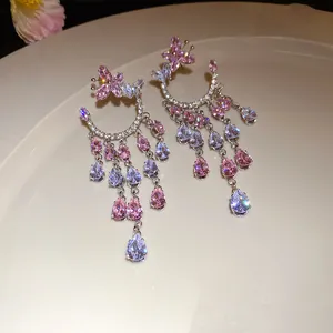 Exquisite close-up of pink zircon butterfly tassel drop earrings on a beige ceramic tray