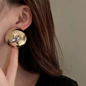 Oversized metallic gold semi-spherical stud earrings with a minimalist high-shine finish