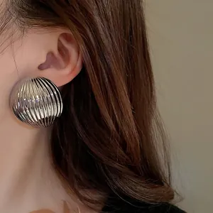 Chunky silver-toned striped domed earrings worn by a model
