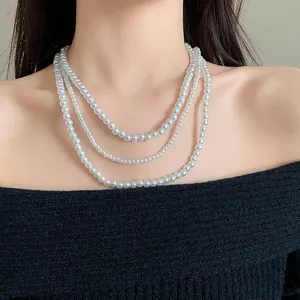 Vista dettagliata di un'elegante collana di perle finte a tre strati su un maglione nero