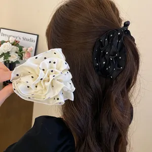 Dettaglio delle mollette per capelli a fiori a pois bianchi e neri sui capelli.