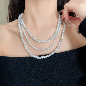 Dettaglio di un'elegante collana di perle finte a tre fili su un maglione nero.