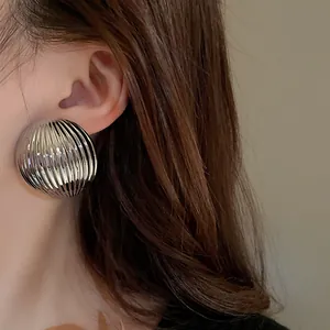 Detailed close-up showing the metallic ribbed texture of large silver semi-circle stud earrings