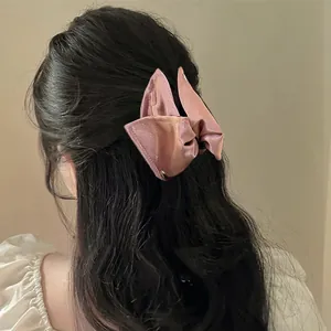 Dettaglio posteriore di un fermaglio per capelli in raso rosa cipria su capelli scuri